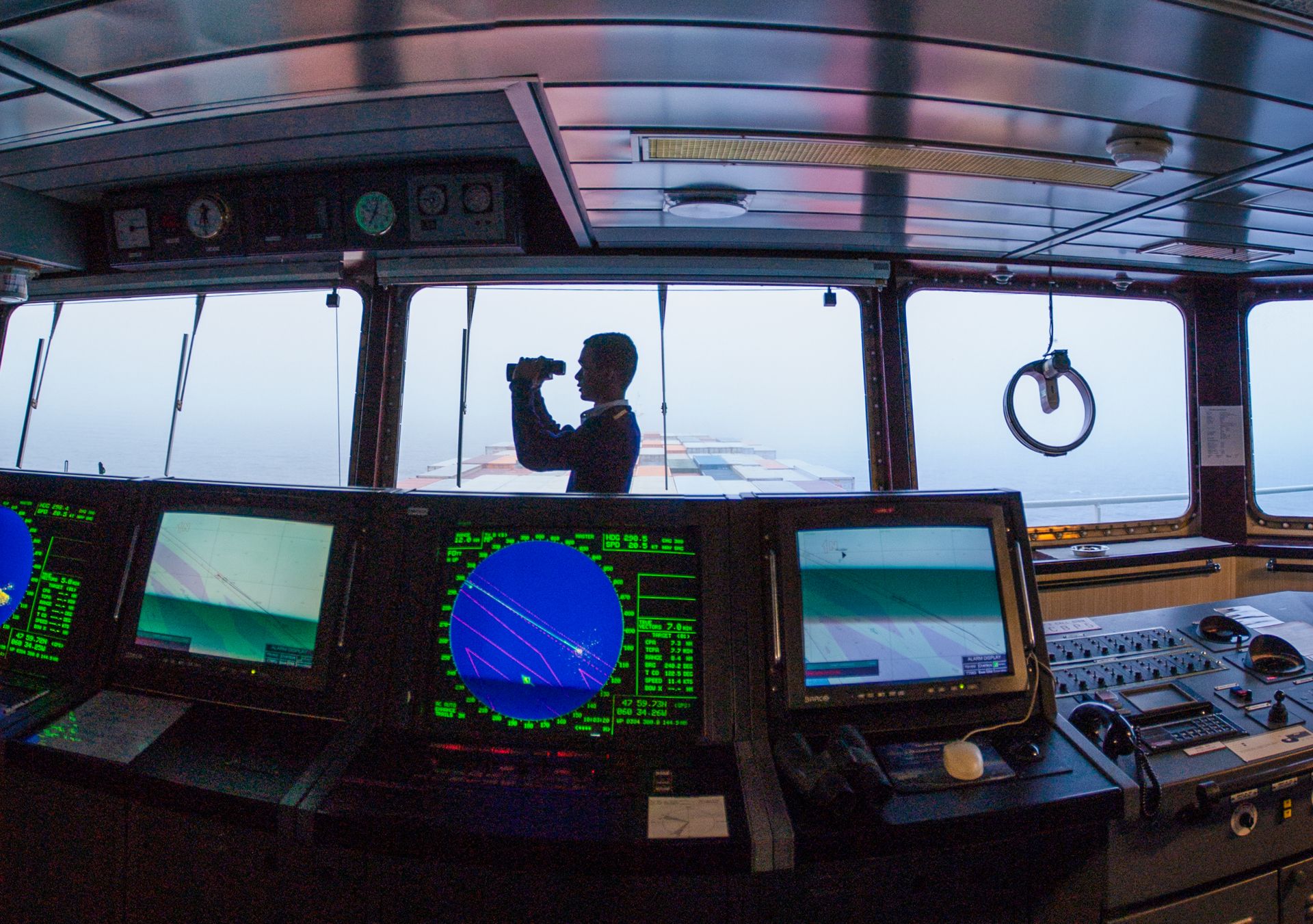 Navigation officer with binoculars on ship bridge